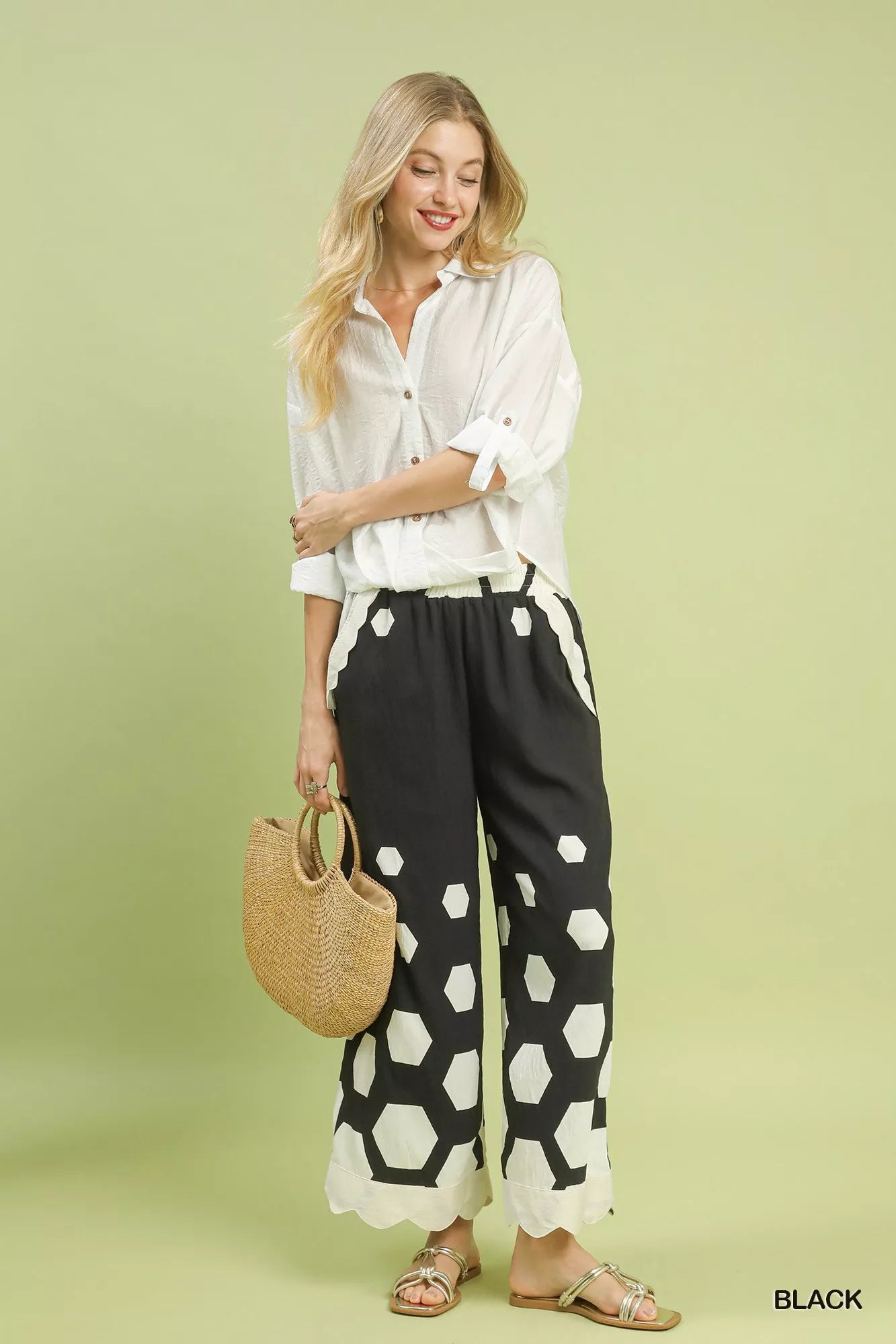 Woman wearing a white shirt and black patterned pants on a light green background