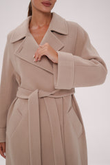 Beige trench coat worn by a person on a white background