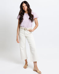 Woman wearing a light purple blouse and white pants on a white background