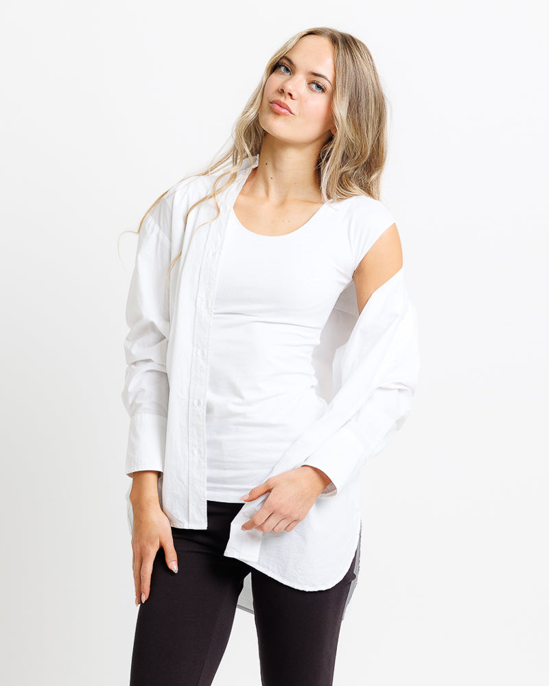 Woman wearing a white shirt and black pants on a plain background