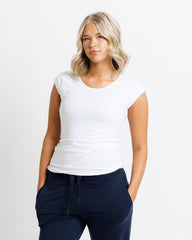 Woman wearing a white t-shirt and navy pants on a plain background