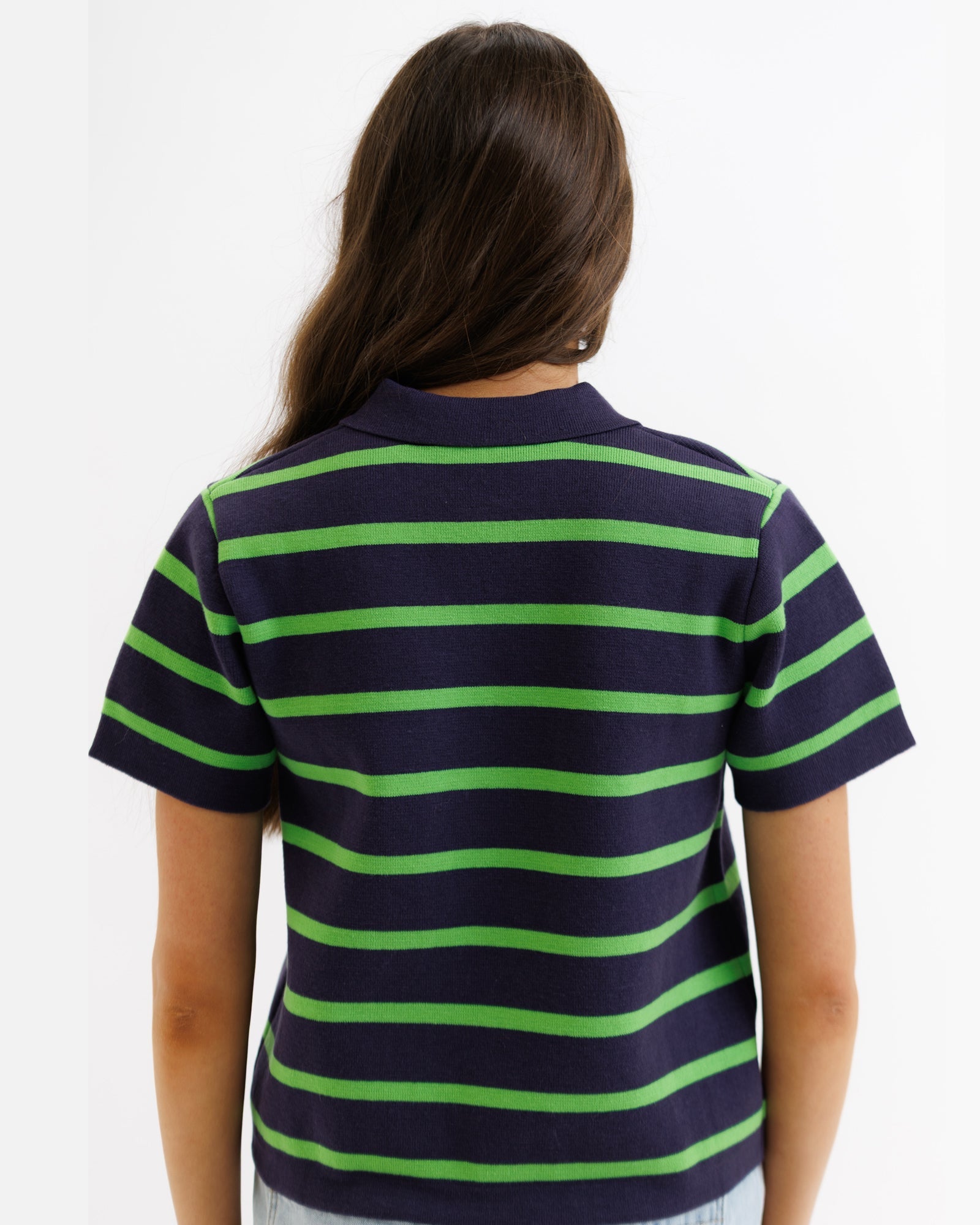 Person wearing a navy and green striped polo shirt on a white background