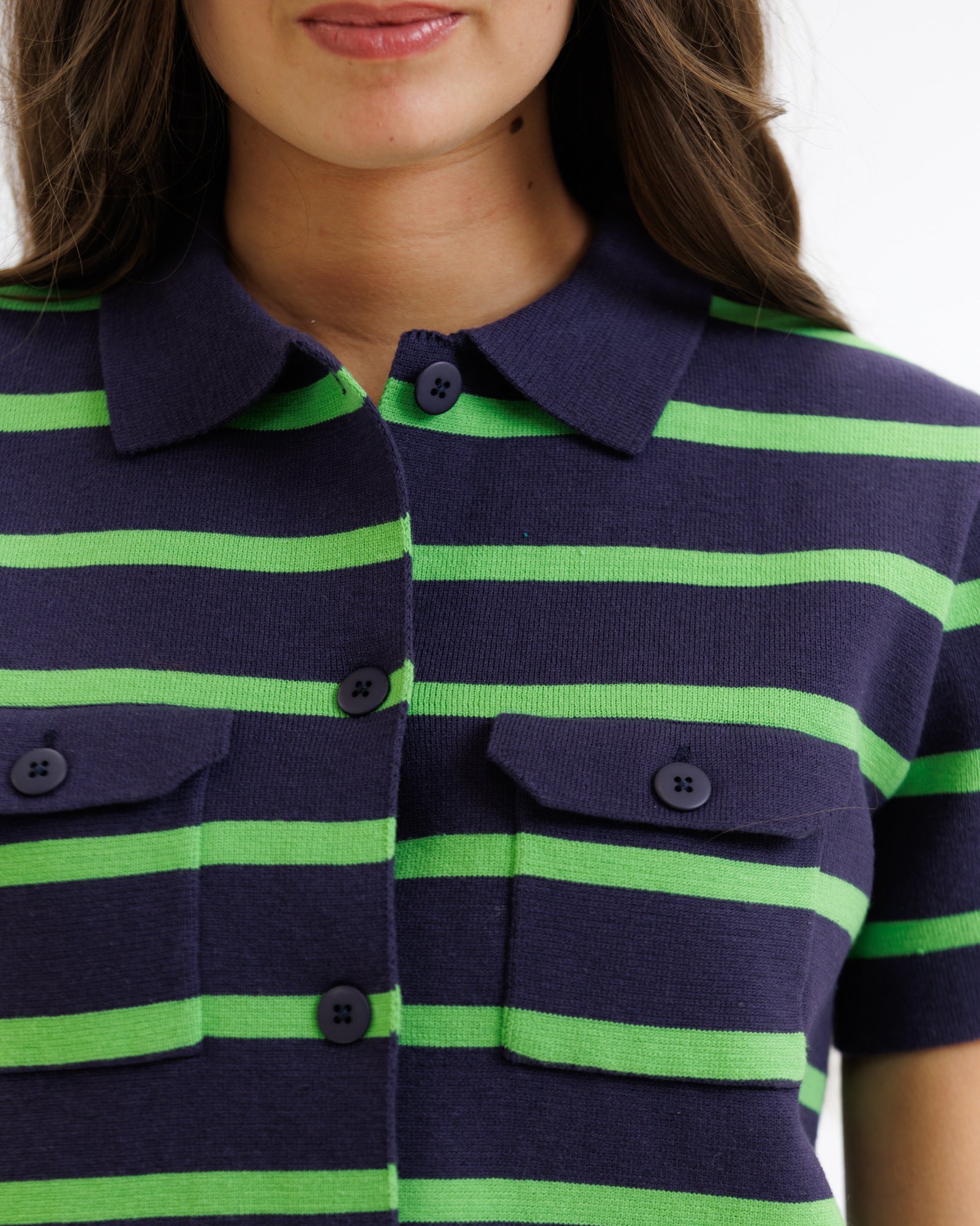 Navy and green striped shirt with button details on a plain background