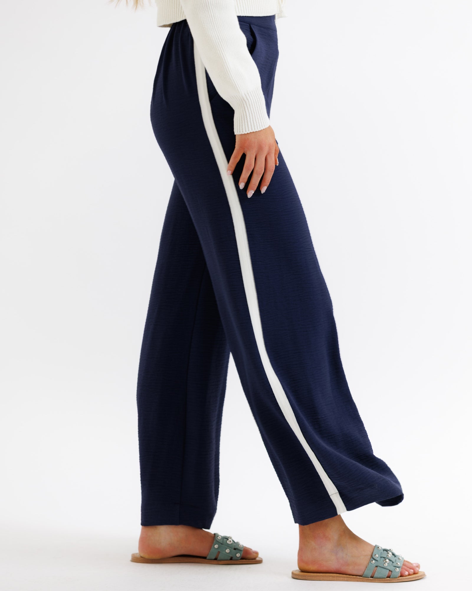 Navy pants with a white stripe worn by a person on a white background