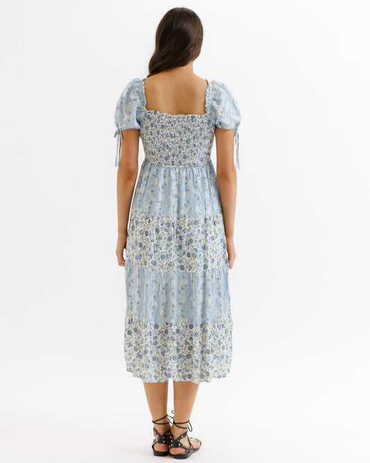 Woman wearing a floral dress with puff sleeves on a white background