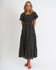 Woman wearing a black polka dot dress on a white background