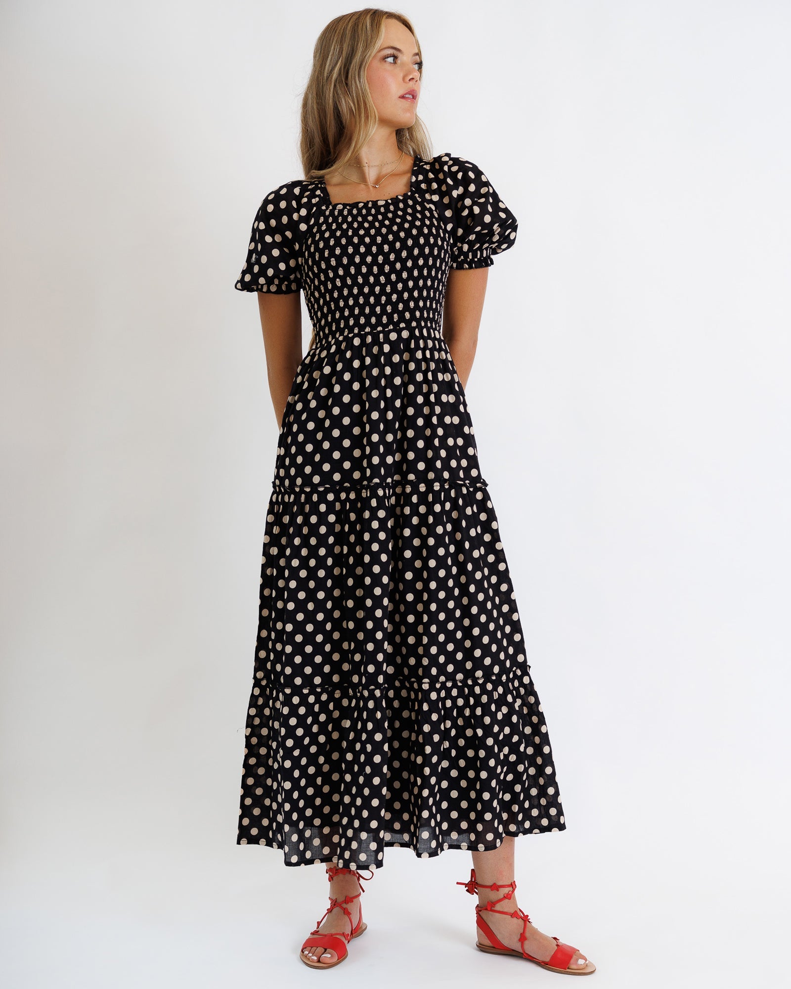 Woman wearing a black dress with white polka dots on a white background