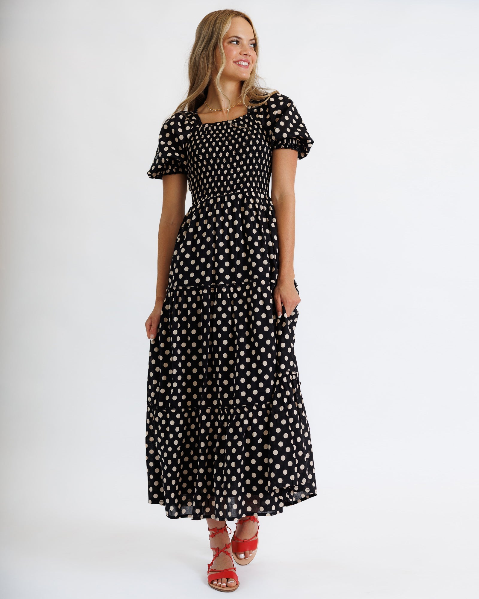 Woman wearing a black polka dot dress on a white background