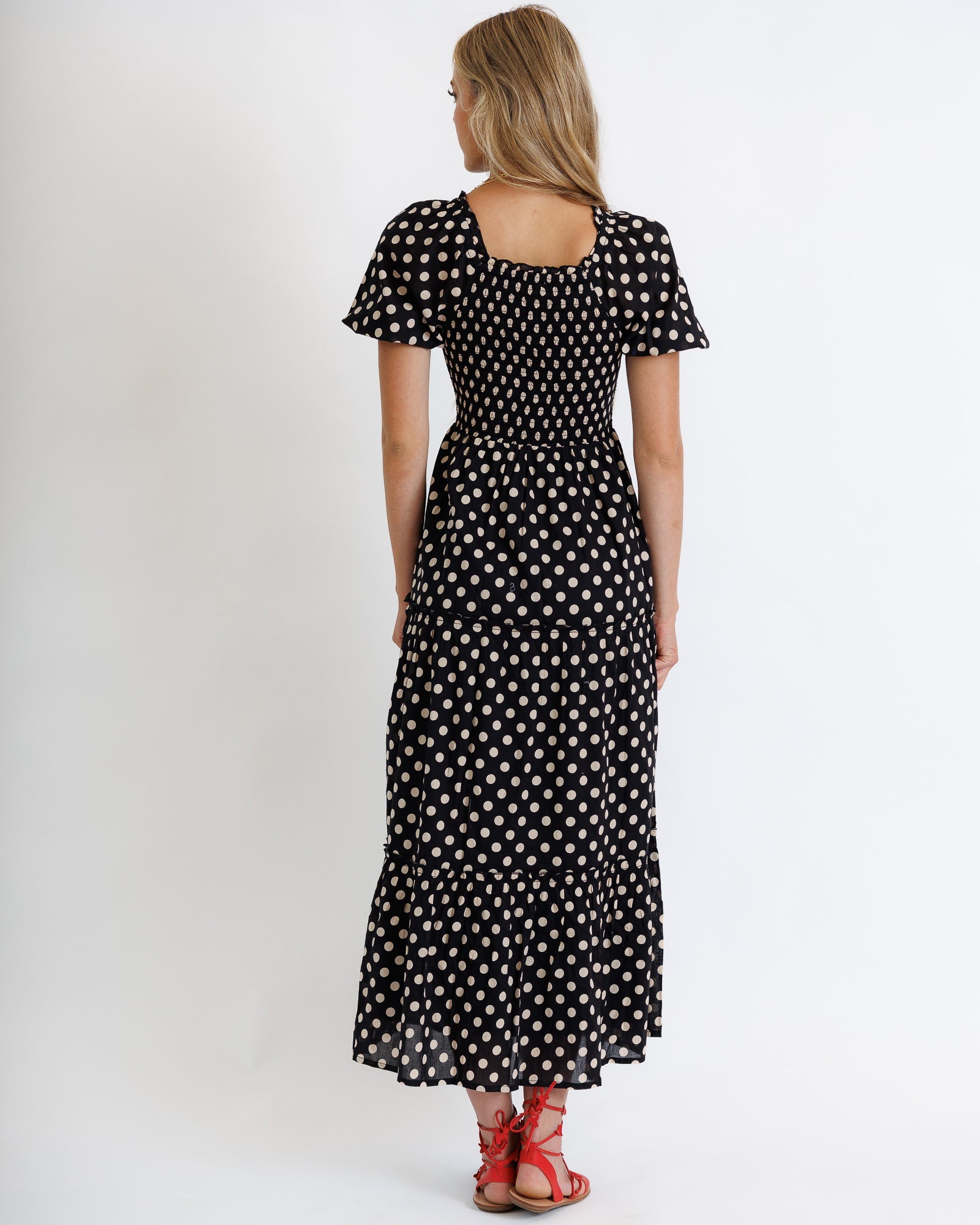 Woman wearing a black polka dot dress on a white background