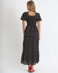 Woman wearing a black polka dot dress on a white background