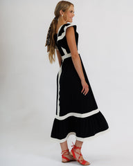 Woman wearing a black and white dress with a cutout back on a white background
