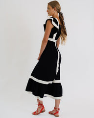 Woman wearing a black and white dress with red sandals on a white background