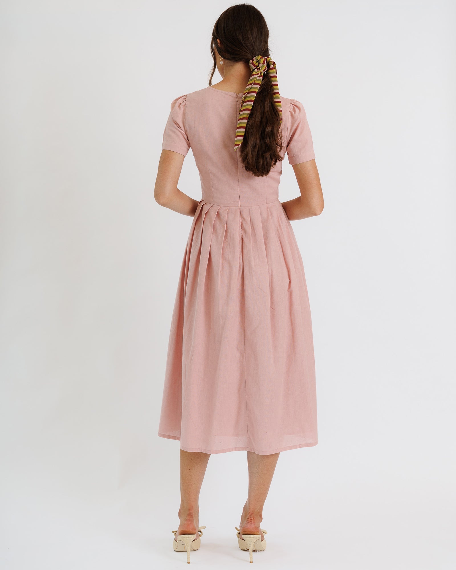 Woman wearing a pink dress with a plain white background