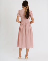 Woman wearing a pink dress with a plain white background