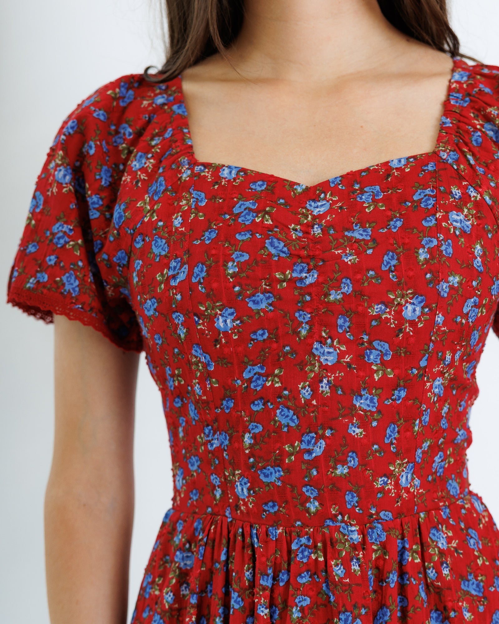 Red floral dress with blue flowers on a plain background