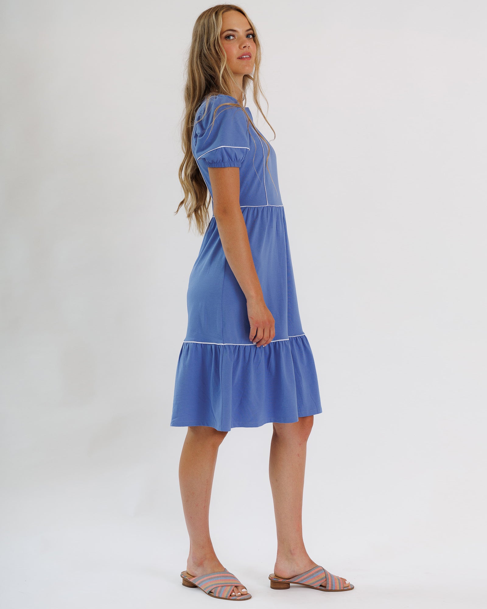 Woman wearing a blue dress with white trim on a white background