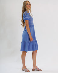 Woman wearing a blue dress with white trim on a white background