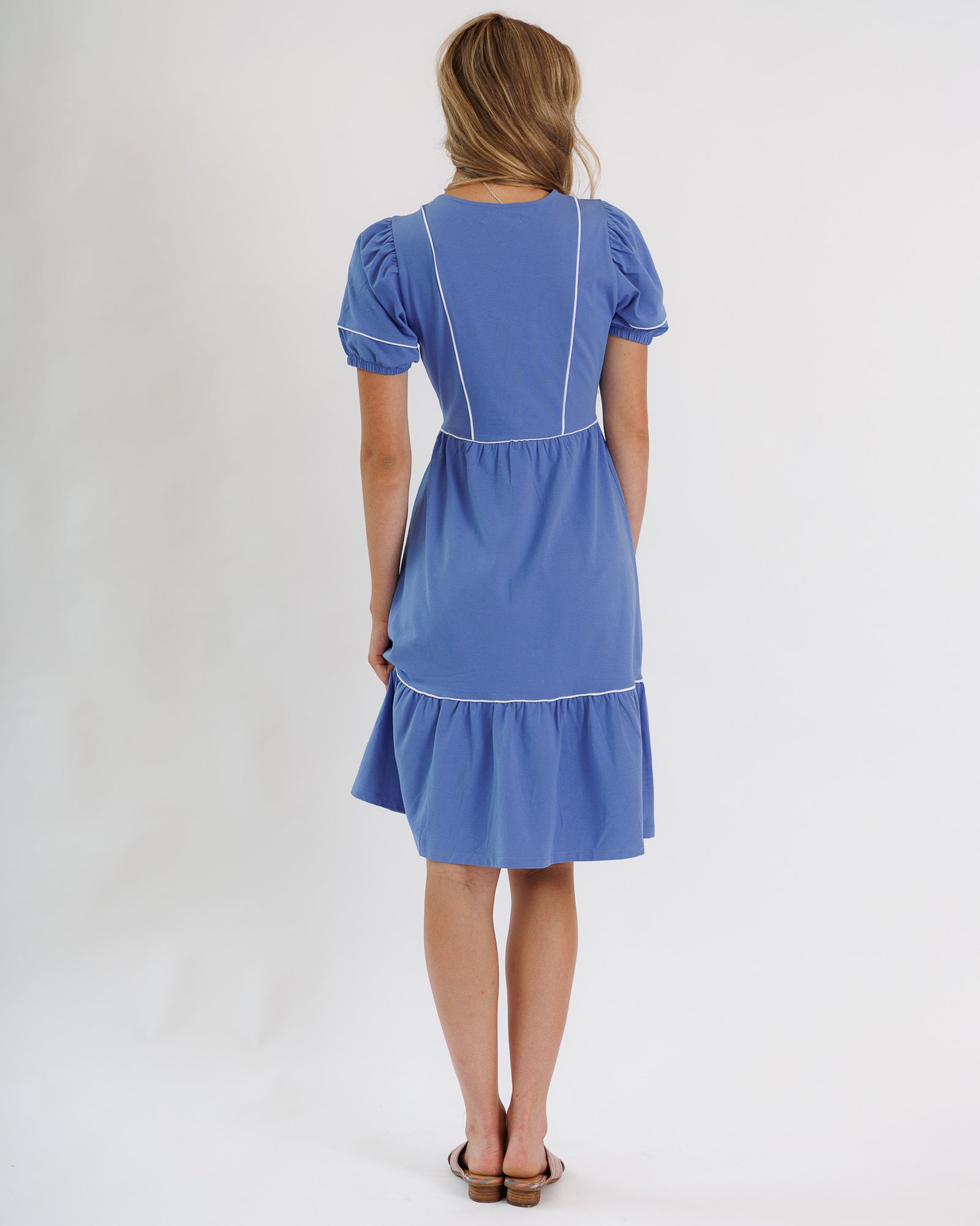 Woman wearing a blue dress with white trim on a white background