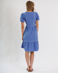 Woman wearing a blue dress with white trim on a white background