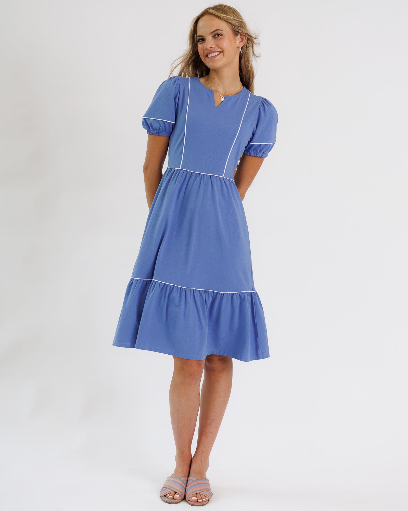 Woman wearing a blue dress with white trim on a white background