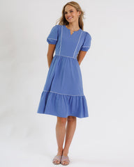 Woman wearing a blue dress with white trim on a white background