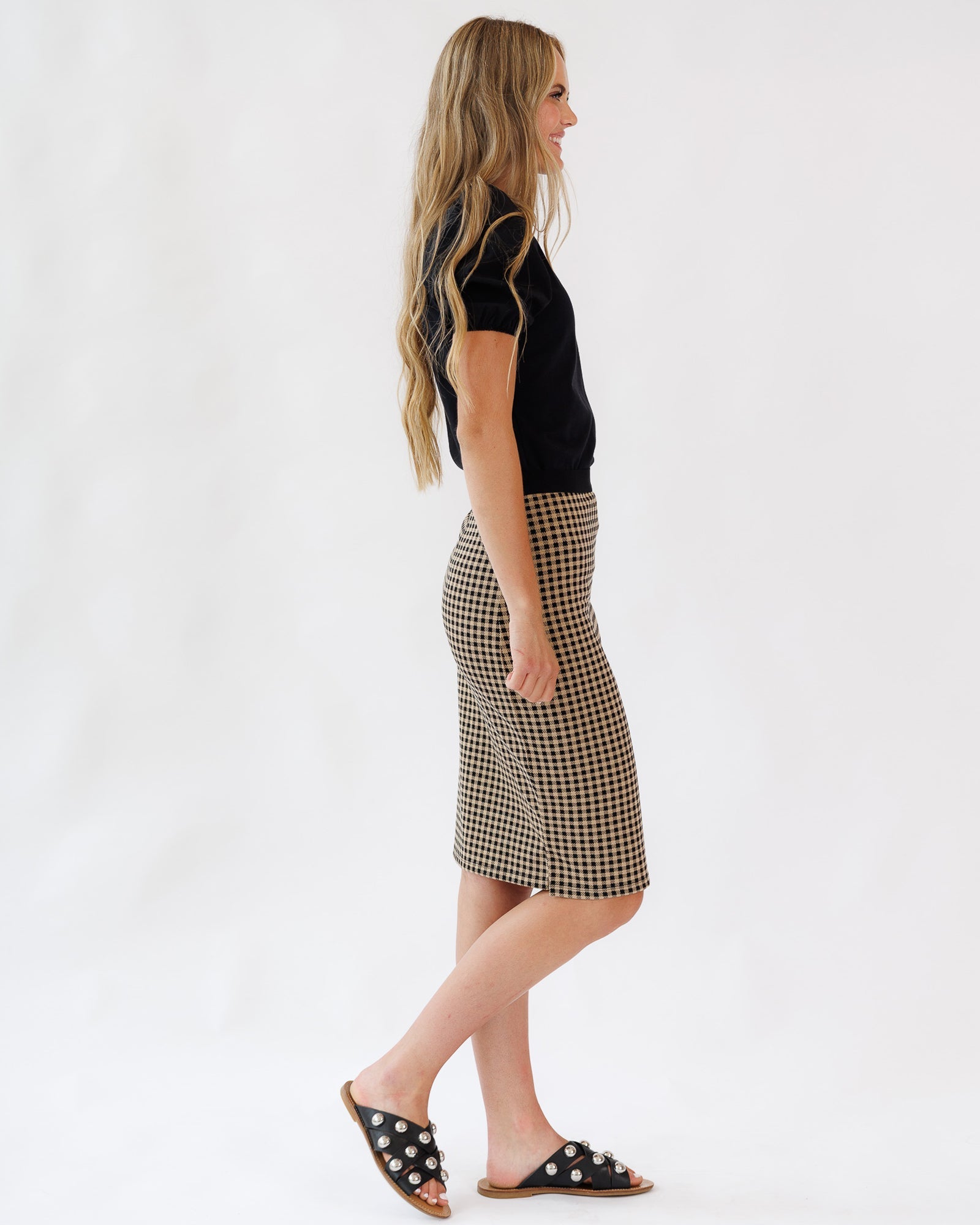 Woman wearing a black top and plaid skirt on a white background