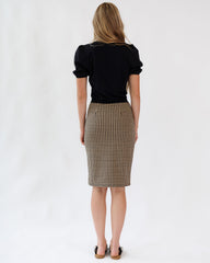 Woman wearing a black top and plaid skirt on a white background