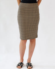 Person wearing a black and beige checkered skirt on a white background