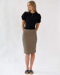 Woman wearing a black top and plaid skirt on a white background