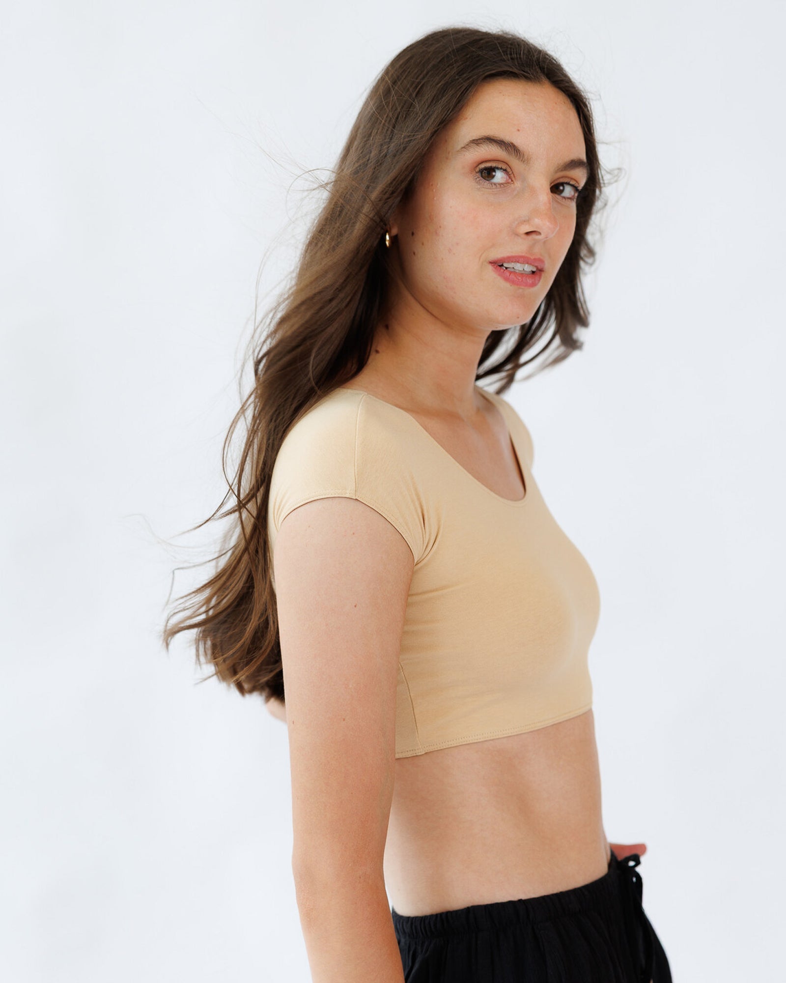 Woman wearing a beige crop top against a white background