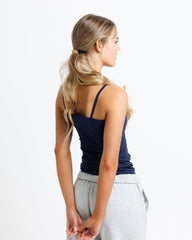 Woman wearing a navy tank top and gray sweatpants on a white background