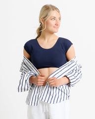 Woman wearing a navy crop top and striped shirt on a white background