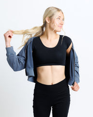 Woman in black athletic wear with a blue jacket on a white background