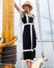 Woman in a black and white dress and straw hat on a sailboat