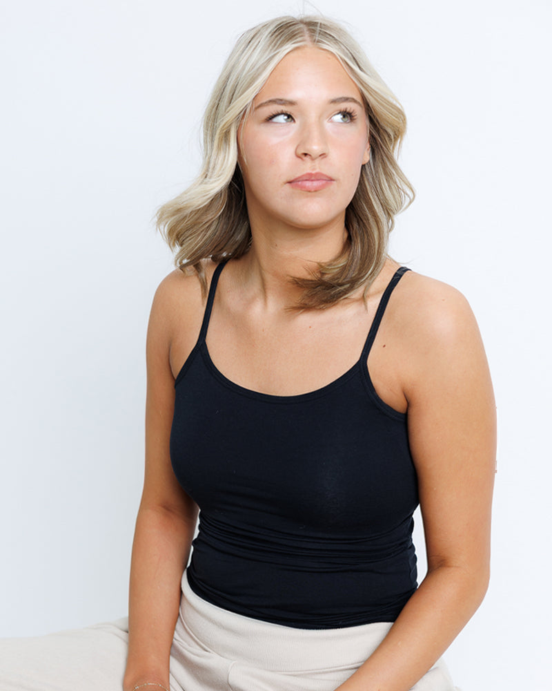 Woman wearing a black tank top against a plain background