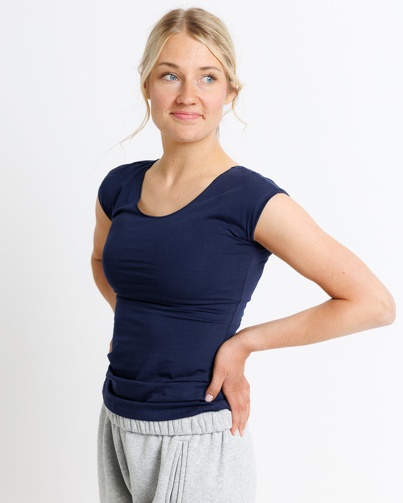 Woman wearing a navy blue top and gray pants on a white background