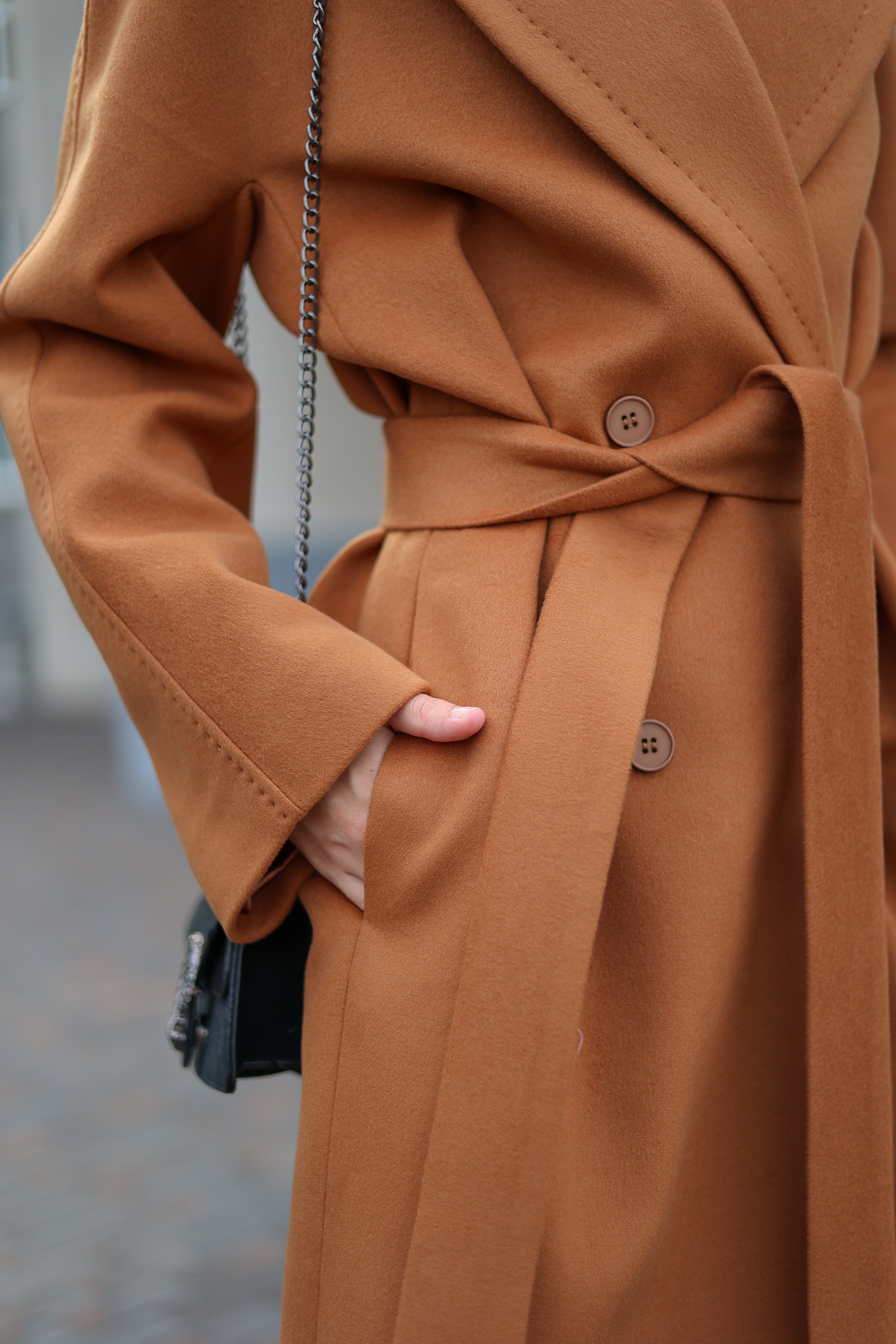 Close-up of a person wearing a brown coat with a blurred background