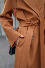 Close-up of a person wearing a brown coat with a blurred background