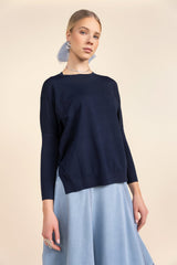 Woman wearing a navy sweater and light blue skirt on a beige background