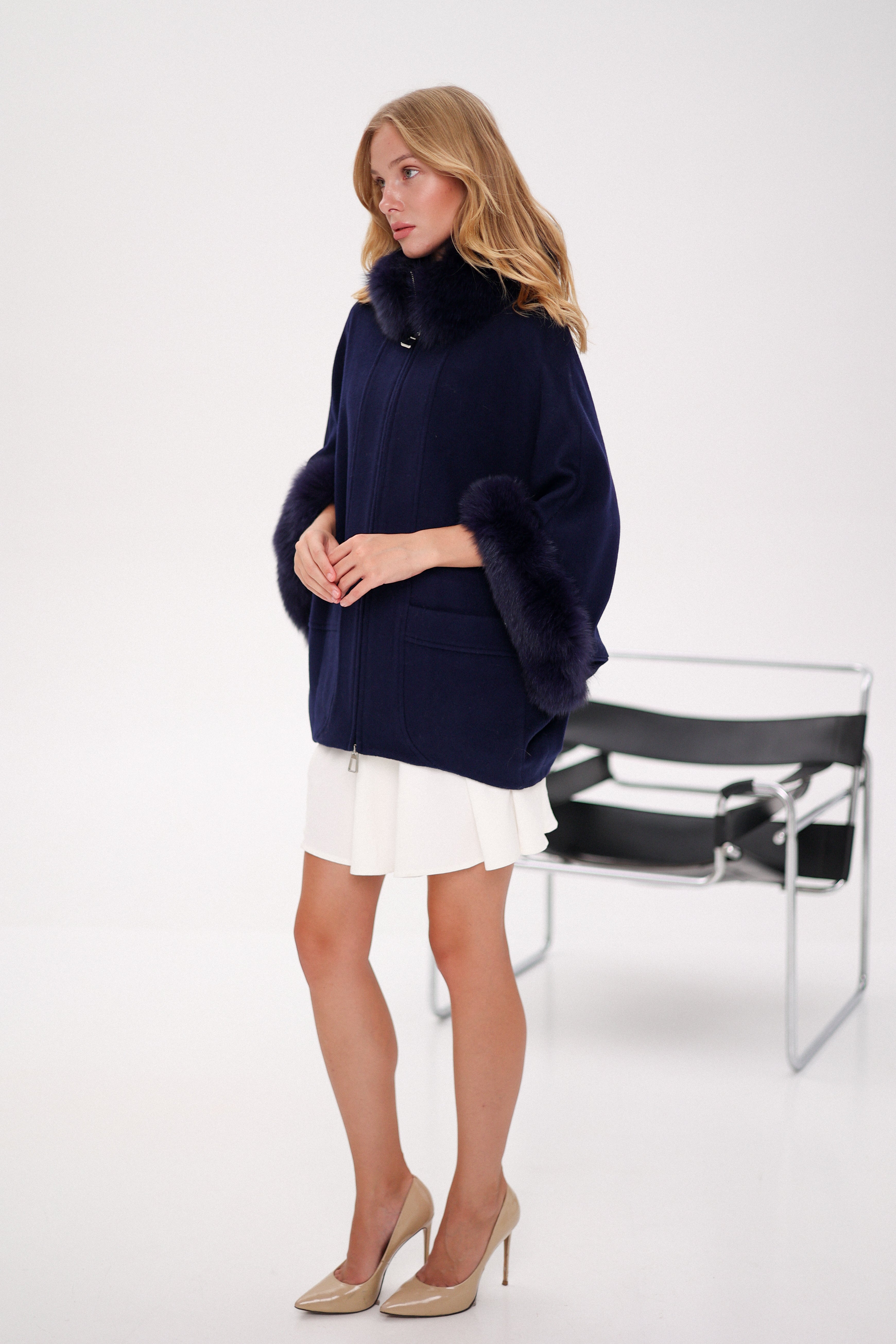 Woman wearing a navy blue sweater with fur trim on a white background