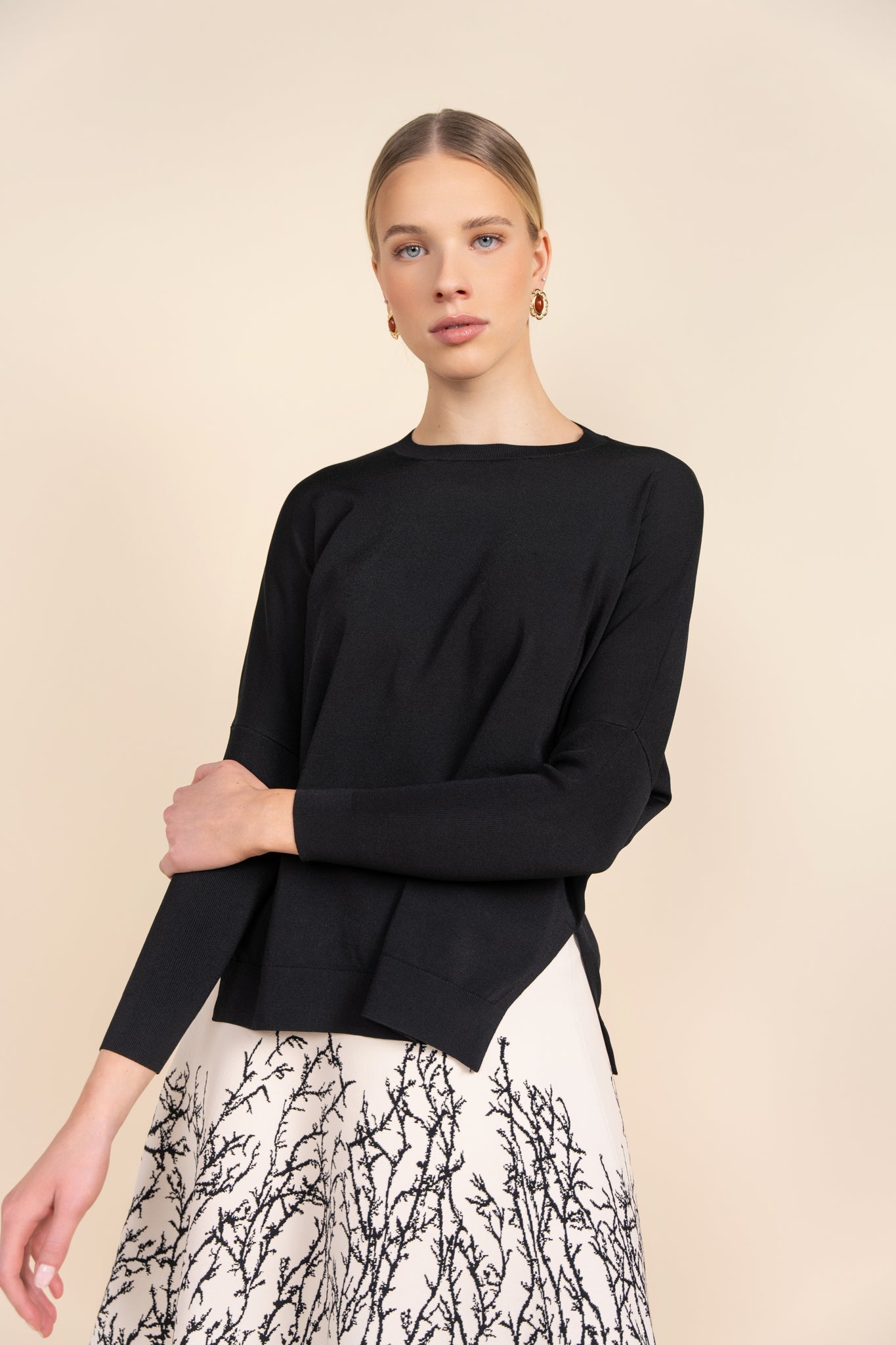 Woman wearing a black long-sleeve top with a beige background