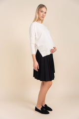 Woman wearing a white sweater and black skirt on a beige background