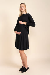 Woman wearing a black dress standing against a beige background