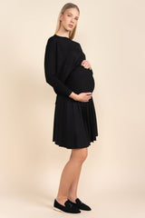 Pregnant woman wearing a black dress against a beige background
