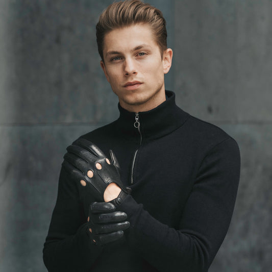 Man wearing a black turtleneck and leather gloves against a gray background