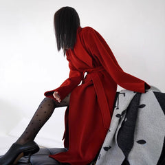 Person wearing a red coat sitting on a chair with a white background