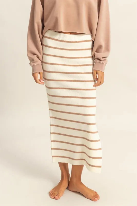 Person wearing a beige and brown striped skirt with a plain background