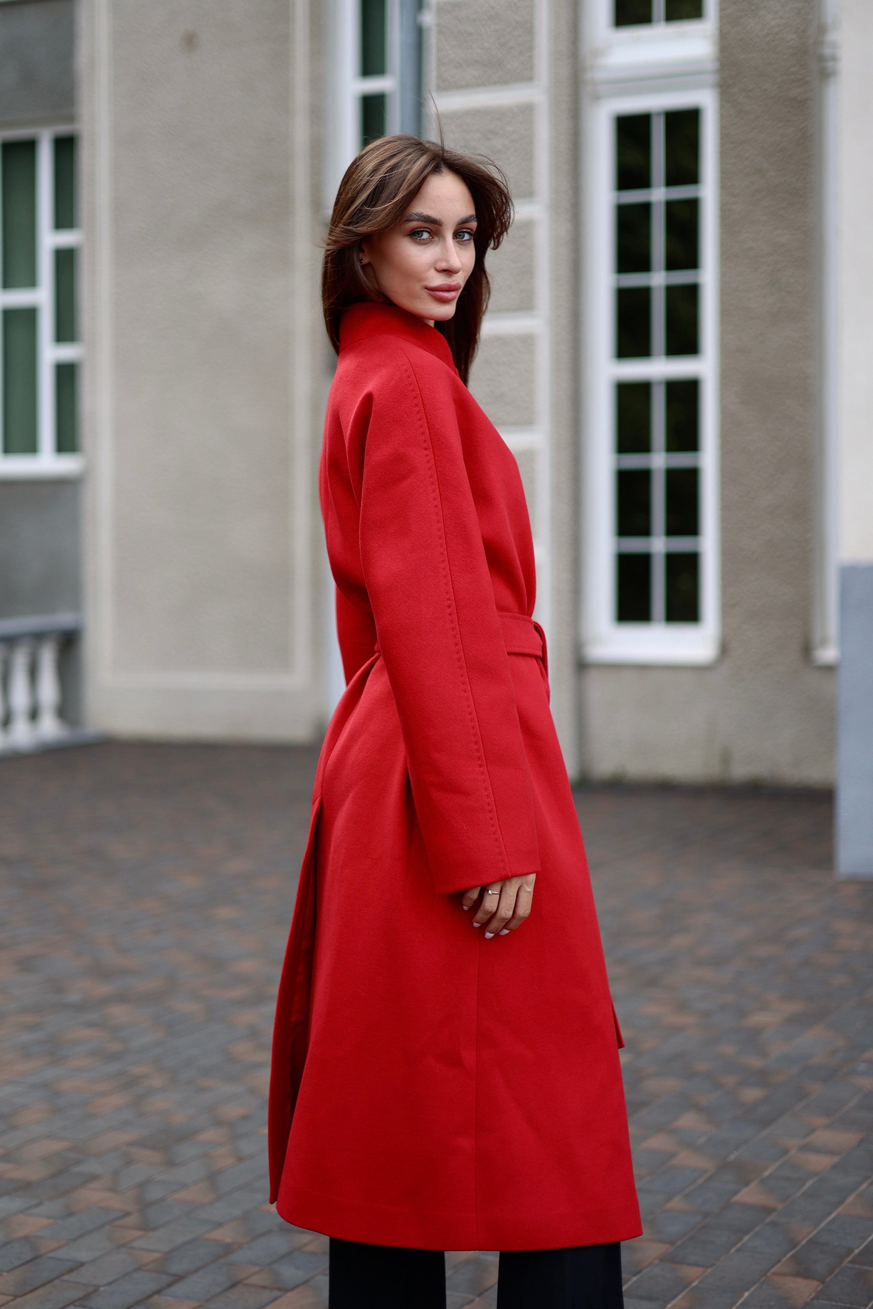 Woman wearing a red coat standing in front of a building.
