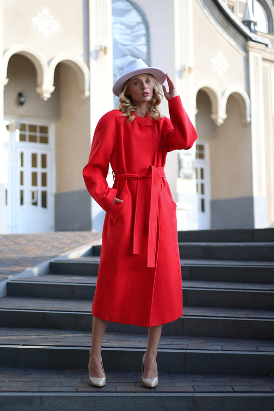 Woman in a red coat and white hat standing on steps outdoors
