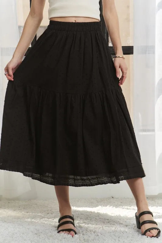 Person wearing a black tiered skirt with a white background